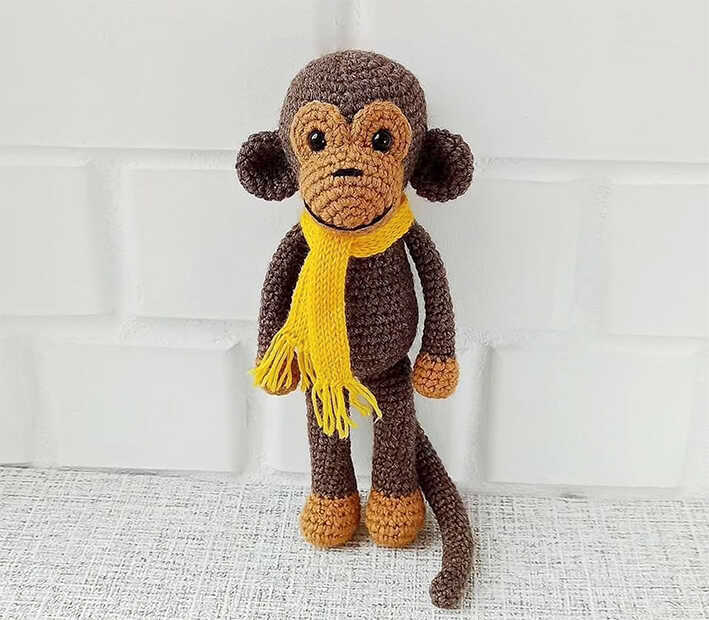 Cute brown amigurumi monkey with long tail and cozy scarf, free crochet monkey pattern perfect for kids gifts and nursery decor
