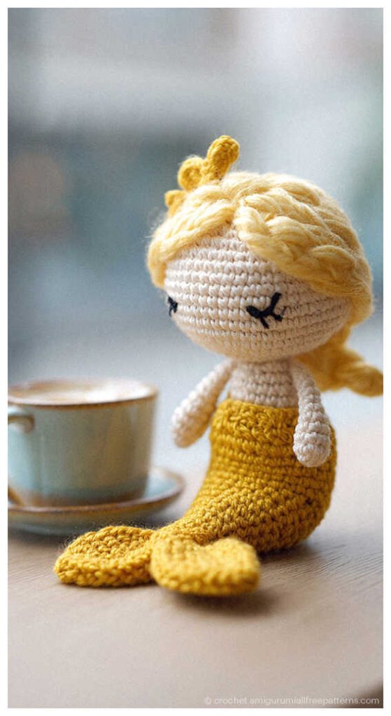 cute yellow mermaid amigurumi doll next to a coffee cup charming handmade crochet ocean toy